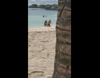 Woman in bikini poses sat on the beach shore