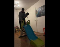 Guy tries to go down slide while holding toddler