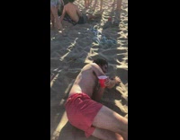 Guy pours beer into friends mouth beach 