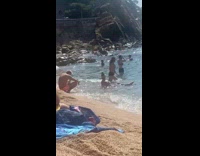 Woman in white bikini sits on the beach shore