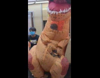 Inflatable dinosaur costume rides subway orange seats 