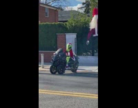 Grinch wearing santa suit on black motorcycle 