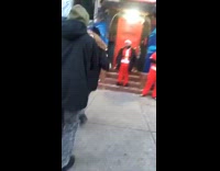 Santa and elves ring bells in front of apartment on the street
