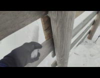 Man Removes Icicle from Fence with Rod