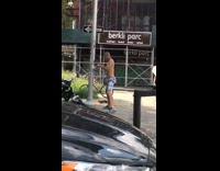 Shirtless guy fights a metal pole on sidewalk