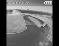 Race car drifts around racetrack on drone camera black and white