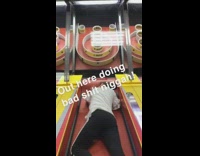 Guy encourages boy to climb into pinball machine and throw ball in jackpot