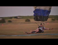 Guy lands on grass with blue parachute 