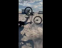 Guy rides bicycle over beach cement steps 