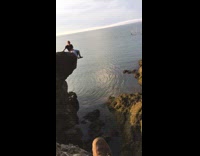 Man on small cliff catches beer can