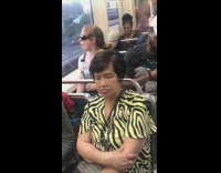 Woman pink shirt sunglasses talks to herself in window reflection on train