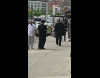 Man offers hand sanitizers on a tray to sidewalk pedestrians