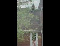 Man in Black Sits on Roof for Photo 