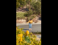 Woman yellow sweater dances front of car