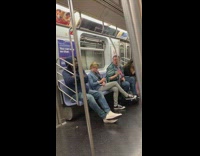 Guy with blue scarf around shoulder lip syncs son on headphones, looks at camera and touches pole