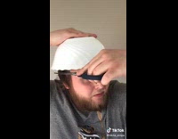 Guy with white bowl on head cutting his hair with scissors