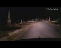 Car drives through cemetery at night 