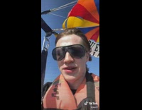 Guy with braces and sunglasses parasailing 