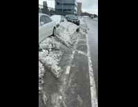 Parked cars covered in dirty snow 