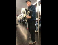 man in blue sweater playing accordion on train