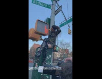 woman sits on street sign light