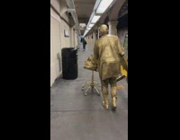 Living statue street performer wheels chair down platform 