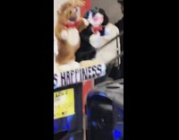 Man plays saxophone with dancing animal puppets in subway station