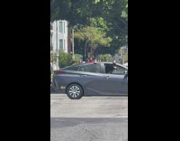 Guy and girl wearing red and green with a stroller dance in middle of street