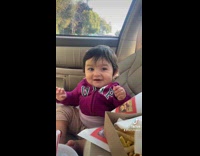 Girl green hoodie in car eating with little baby 