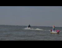 Guy rides white jet ski around beach 