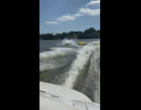 Two people tubing in lake go airborne after wave
