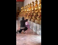 Woman violet dress poses front of statues