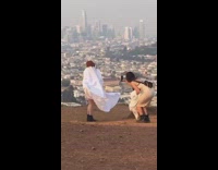 Woman in a white blanket poses on the hill