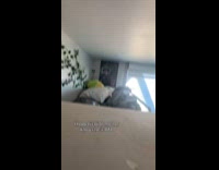 Woman hiding from her cat behind cushion