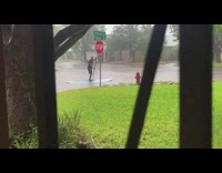 Man in shorts on paddle board raining flooded streets