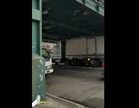 Large white truck gets tuck under bridge 