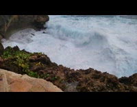 Guy film beach coastline large crashing waves