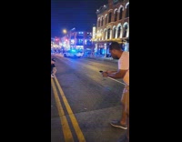 Man poses in the middle of the street with the police behind