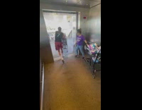 Guy pushing a shopping cart full of cases of beer out of elevator