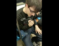 Guy shaves face on train black shirt 