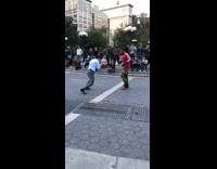 Man in business suit fights red jacket with boxing gloves in a crowd at the park
