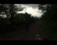 Guy and friend ride bicycles down dirt