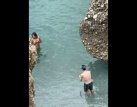 Topless woman cover breast beach large rock