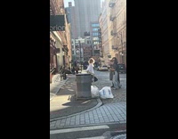 Woman poses on fence beside trash bins