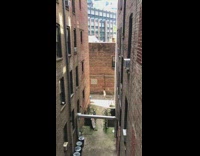 A girl hops in alley between buildings