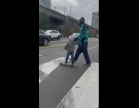 Little boy on skateboard rides over sidewalk 