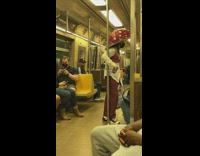 Lady riding subway wears red mushroom hat 