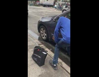 A man shaves his beard using car mirror