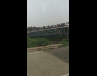 Train with many people on the rooftop passes the crossroad