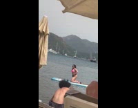 Woman bikini kneels on surfboard at beach